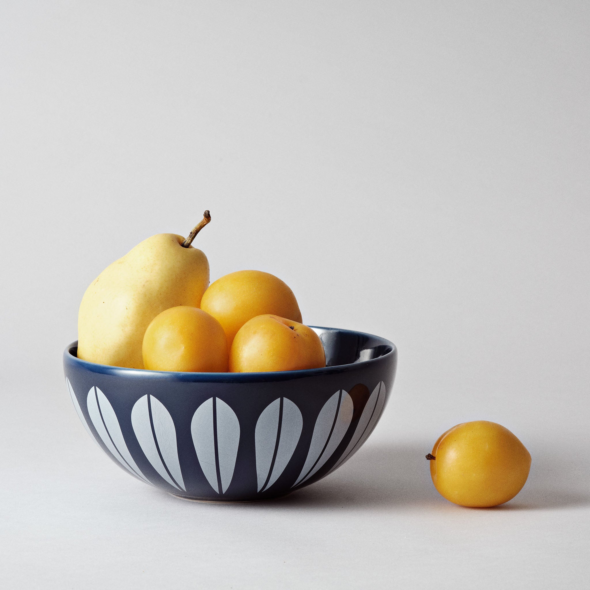 Image of Lucie Kaas's Arne Clausen decorative bowl in dark blue filled with yellow fruit