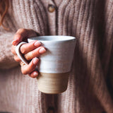 Person holding a ceramic mug with a neutral background