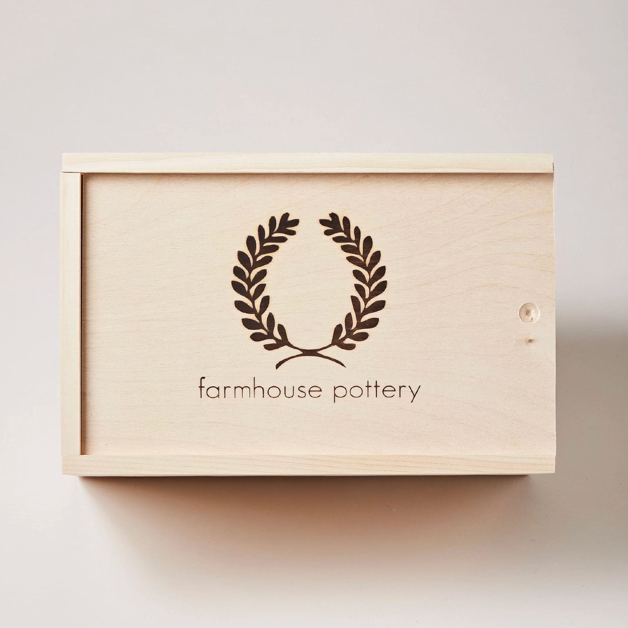 Wooden box with 'farmhouse pottery' logo on a light background