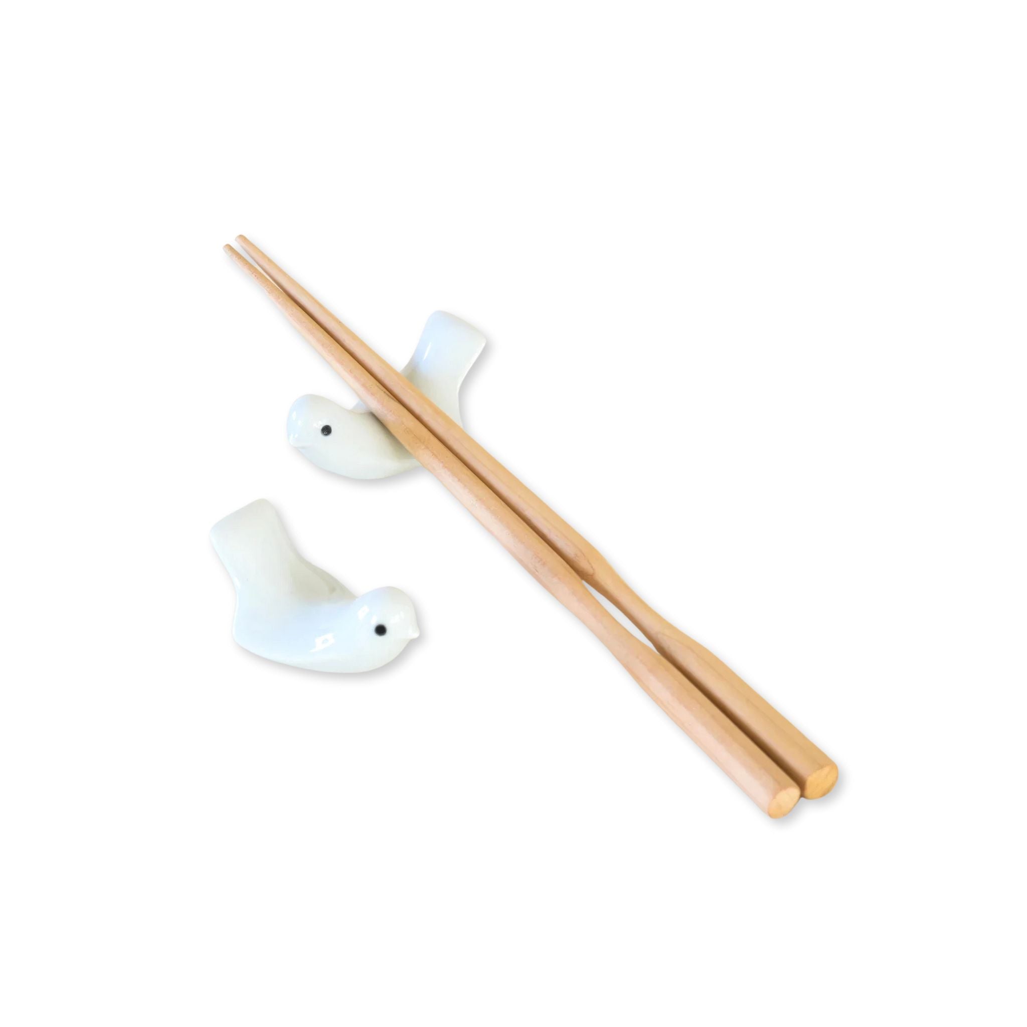 A pair of wood chopsticks rests on one lovebird chopstick holders on a white background