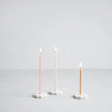 Image of 3x Wishing Candles lit on Wishing Candle holders on a light background