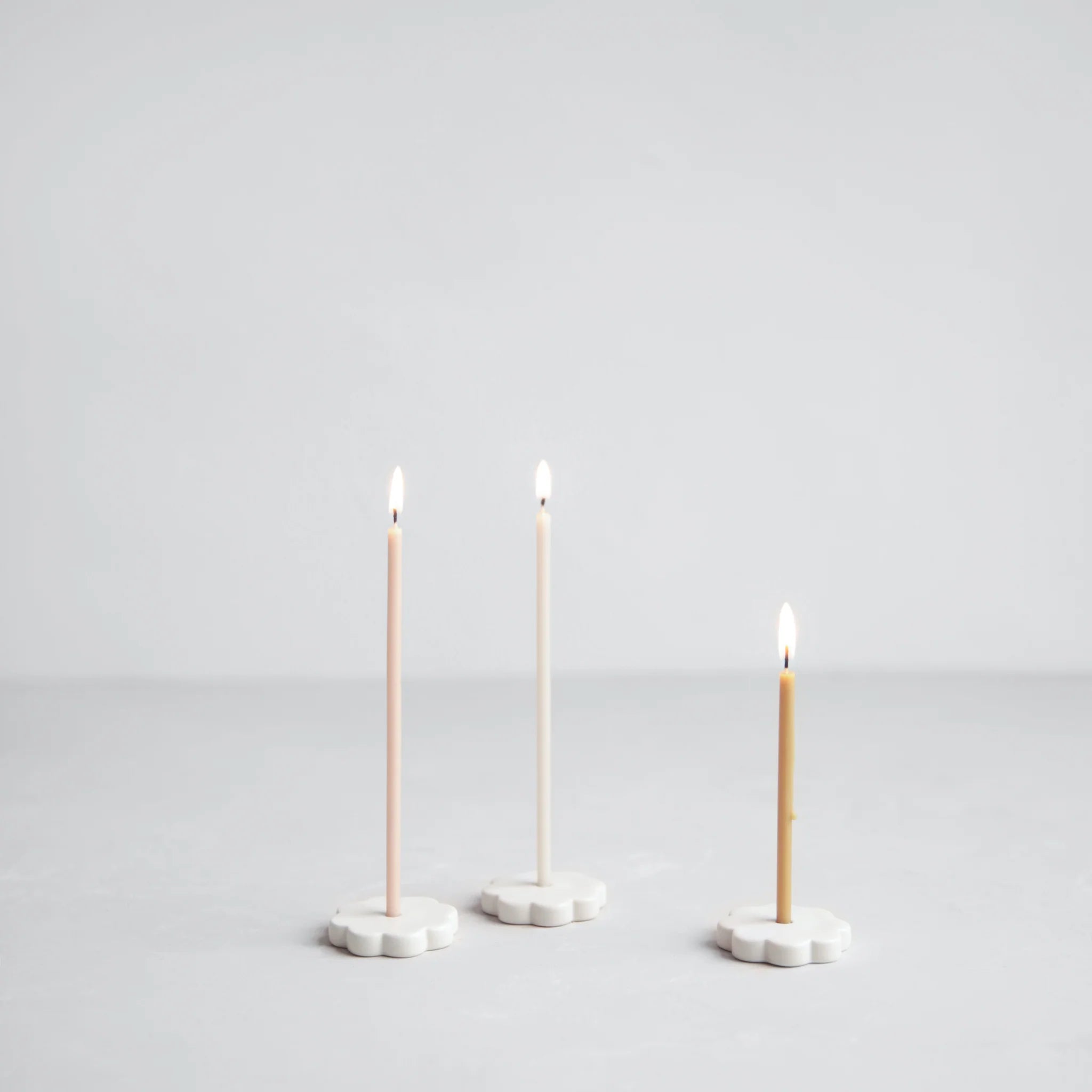 Image of 3x Wishing Candles lit on Wishing Candle holders on a light background