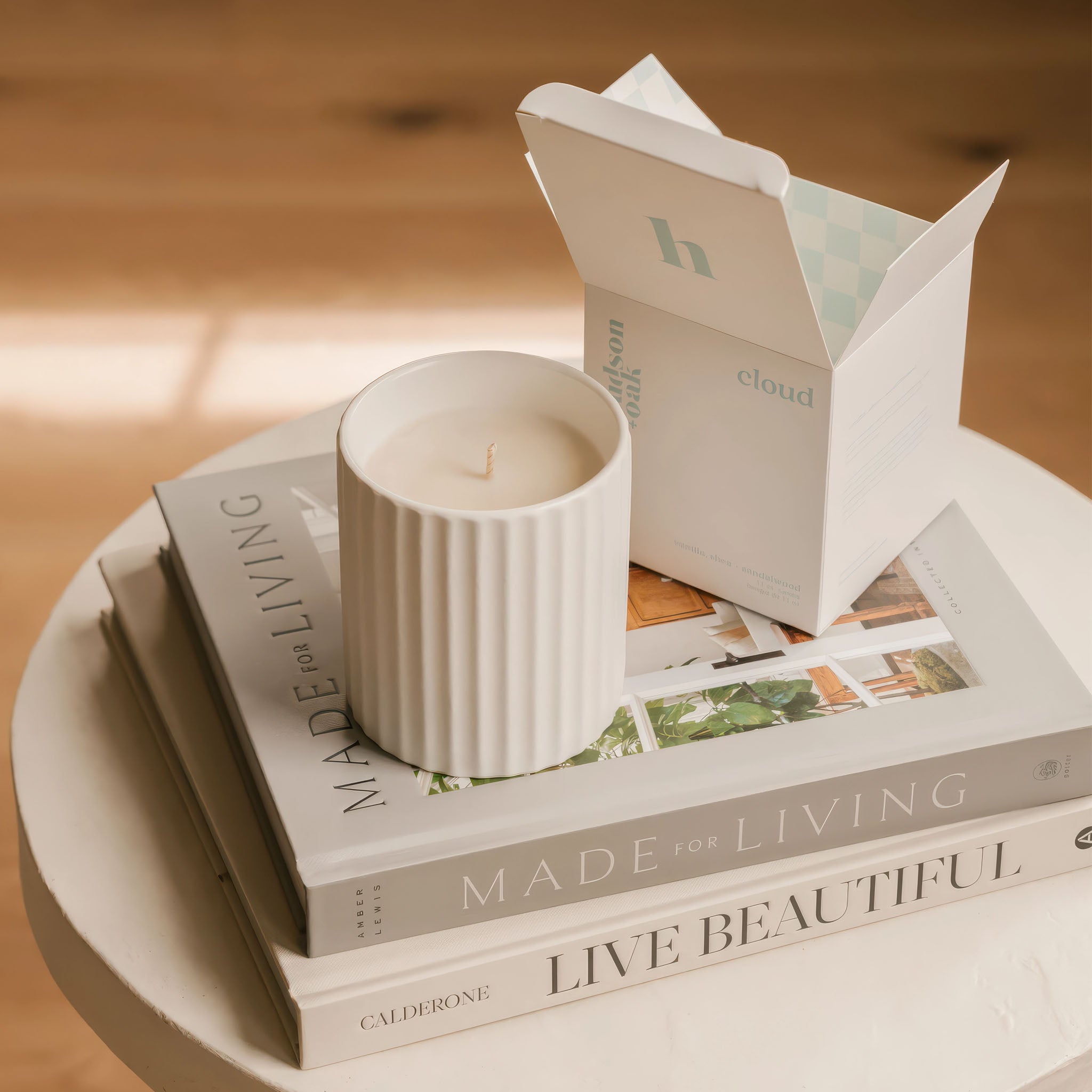 lifestyle image of hudson oak scented candle cloud next to box ontop of books