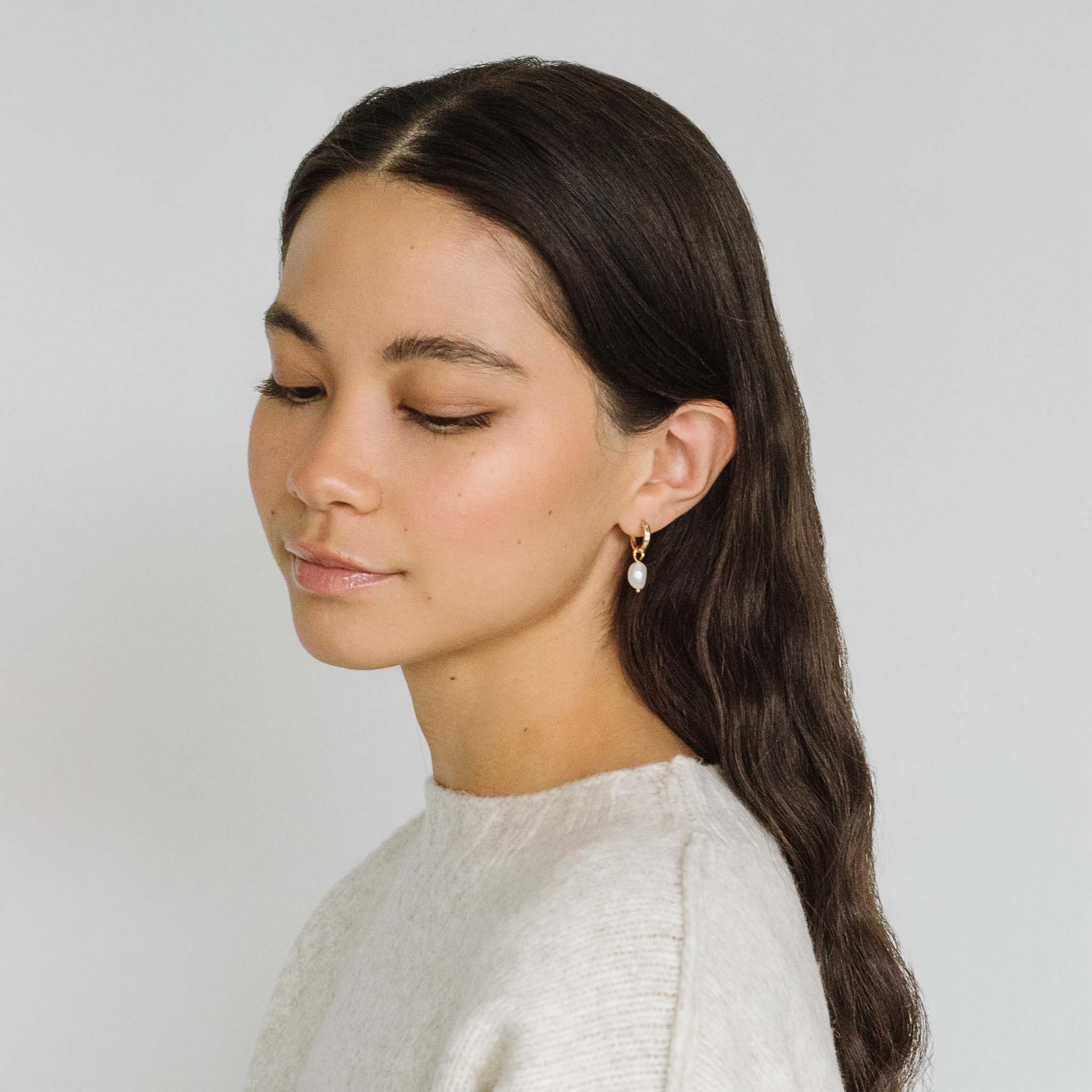 A model wearing Kara Yoo's Anna hoops + Pearl Drop Charms earrings