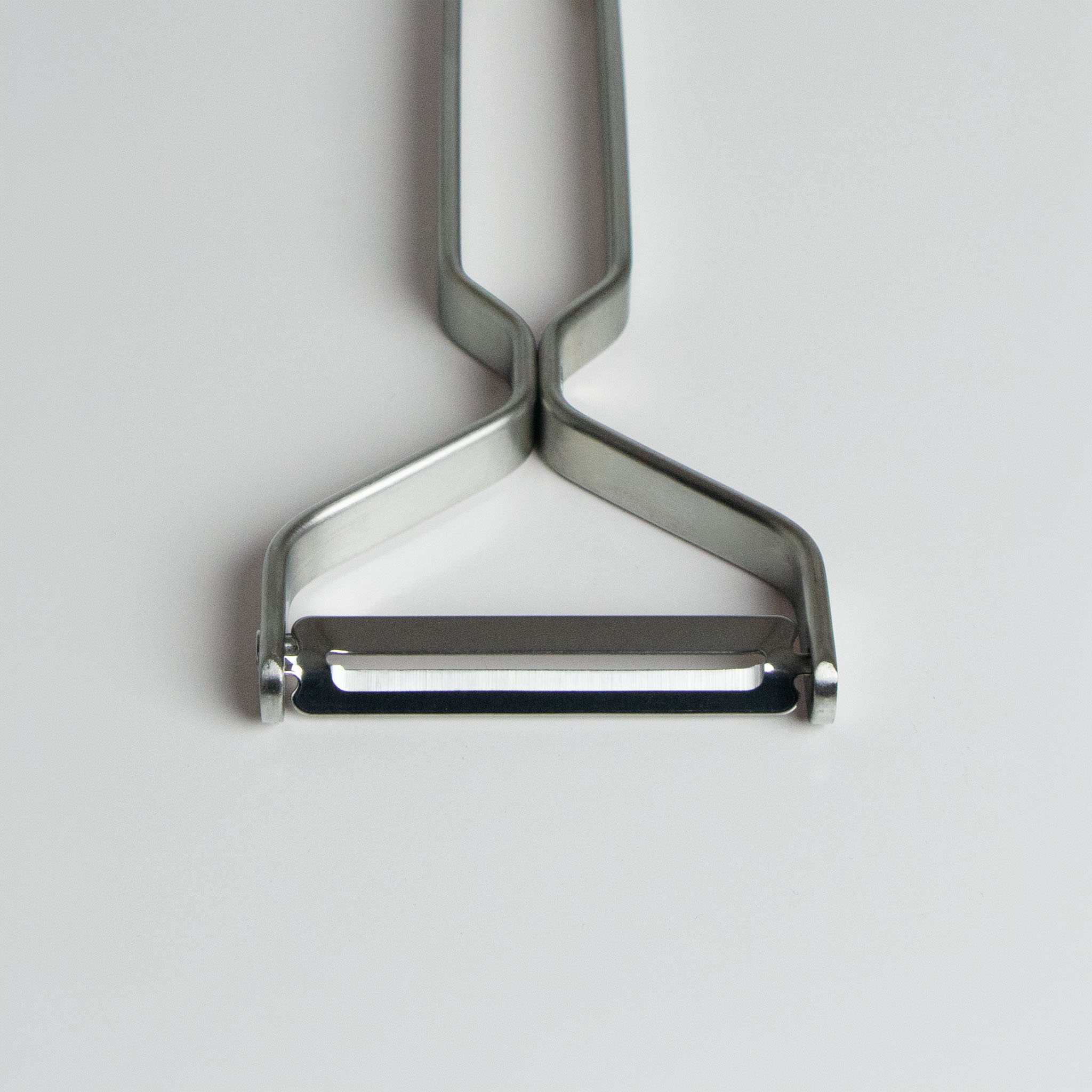 Close up of the Yoshita stainless steel peeler on a light gray background