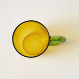Top down view of yellow glass mug on a white background