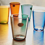 Set of colorful glass tumblers on a reflective surface