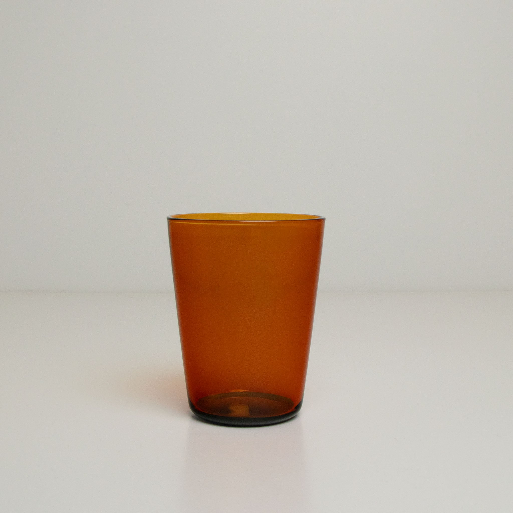 Two toned amber glass tumbler on a white background