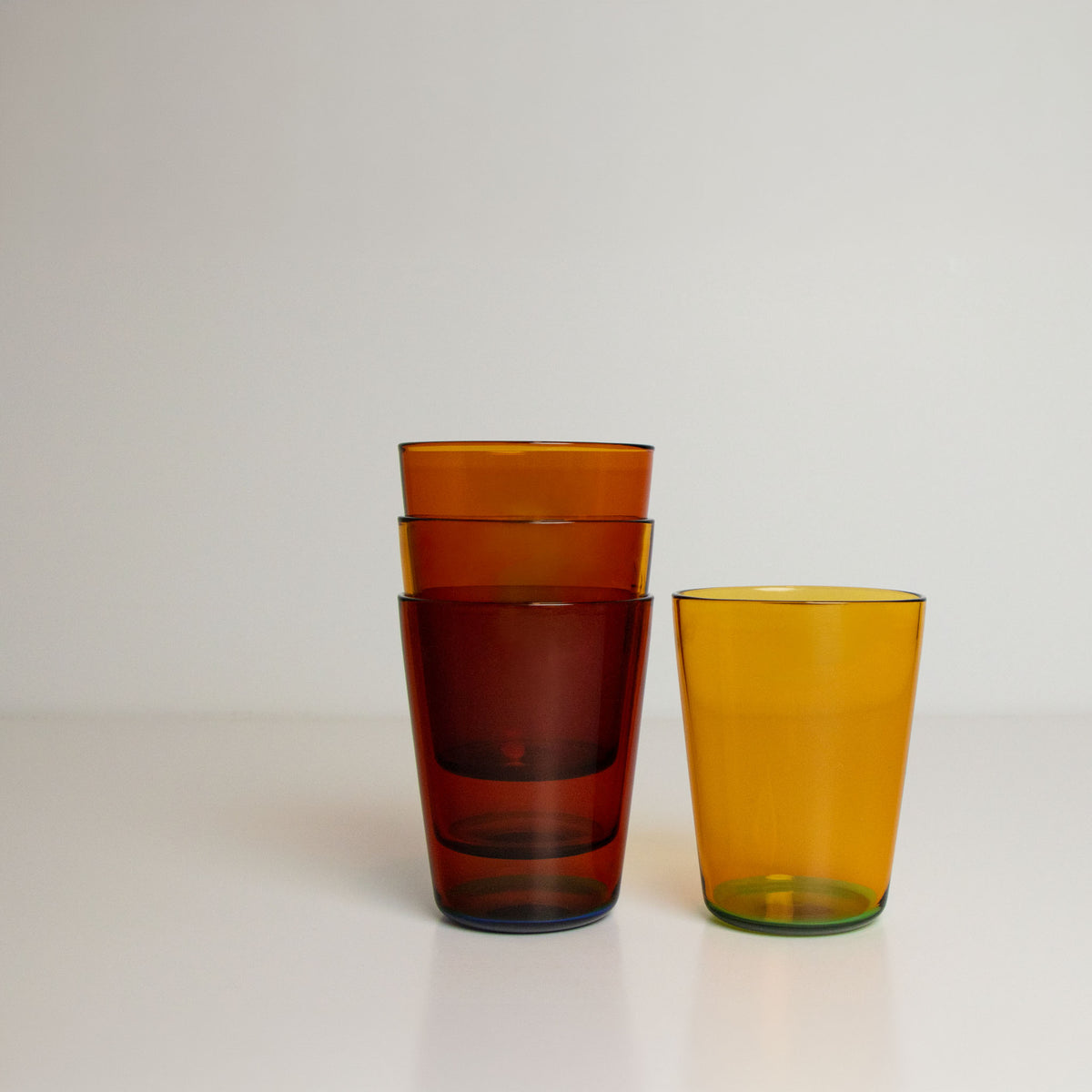 Set of four two toned stackable glass tumblers on a white background