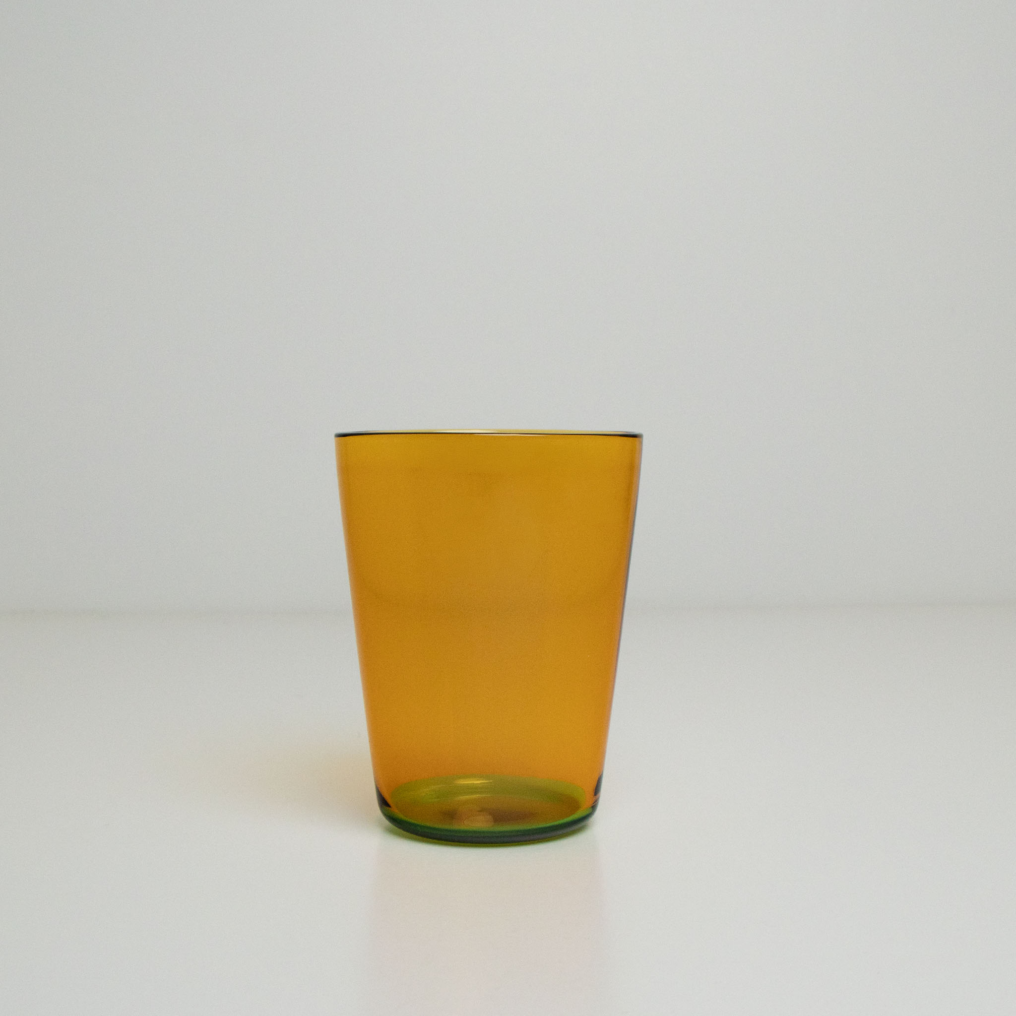 Two toned yellow and green glass tumbler on a white background