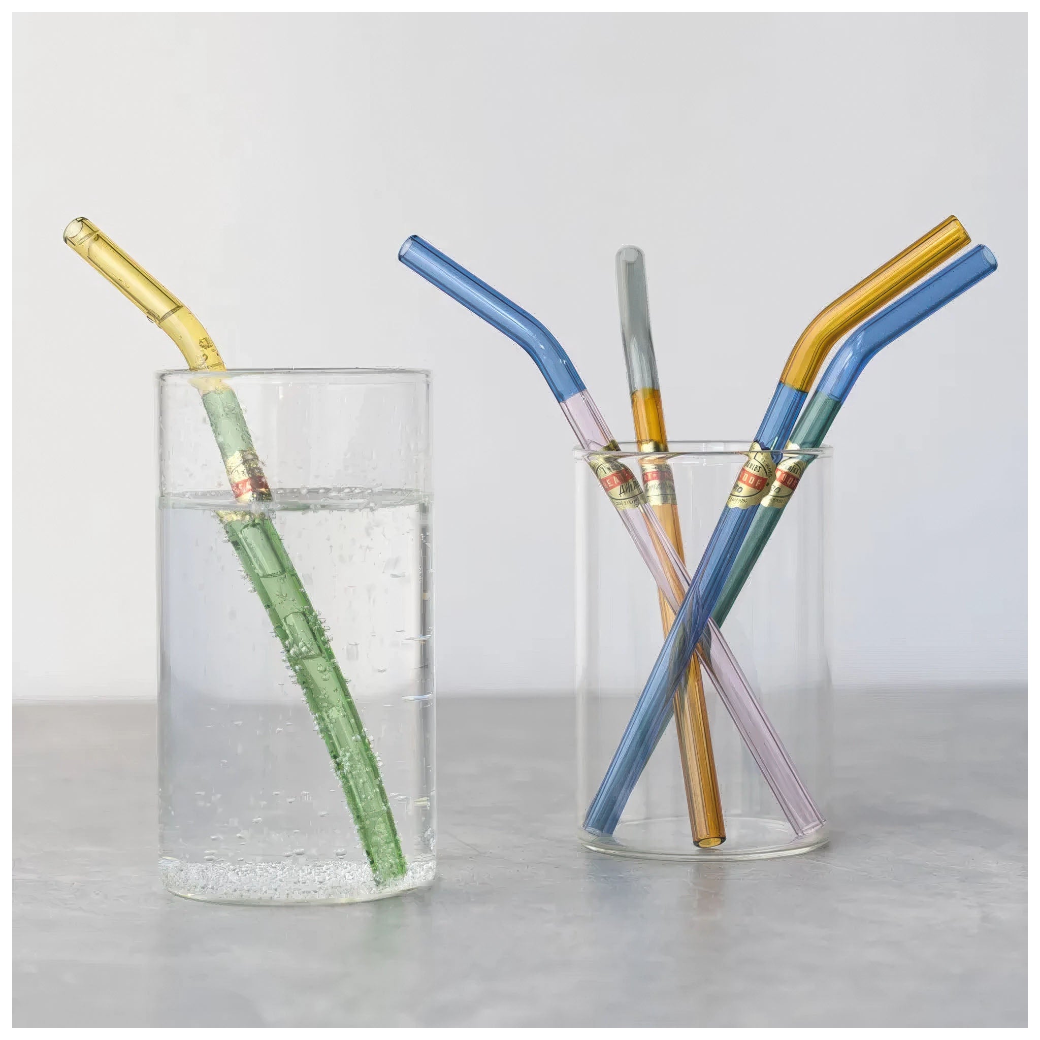 Colorful straws in glass containers on a light gray background
