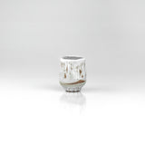 Handmade ceramic sake cup with white drip glaze and ribbed base in natural clay tones, by The Lazy Potters.