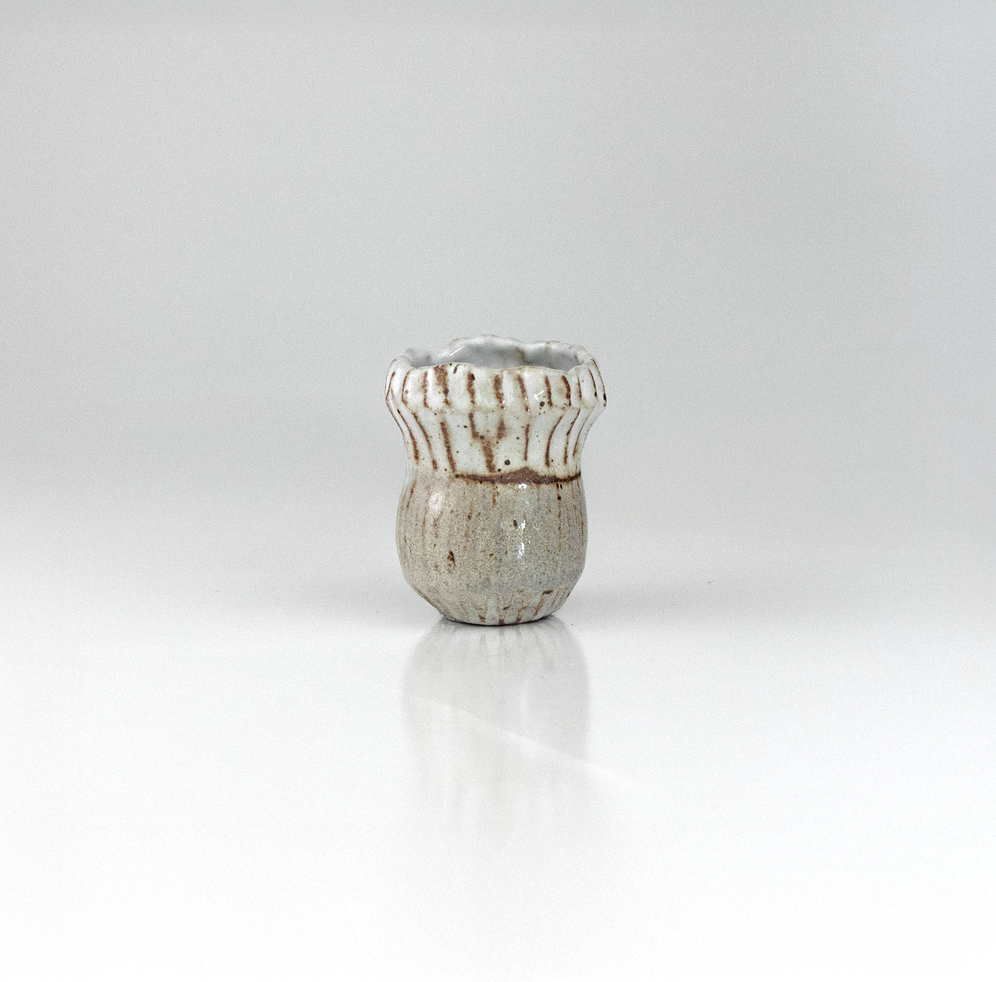 Handcrafted fluted ceramic sake cup with white glaze and ribbed texture, by The Lazy Potters.