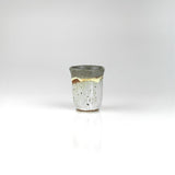 Handmade ceramic sake cup with layered grey and ochre glaze and speckled texture, by The Lazy Potters.