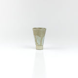 Tapered handmade ceramic sake cup with pale celadon glaze and raised clay foot, by The Lazy Potters.