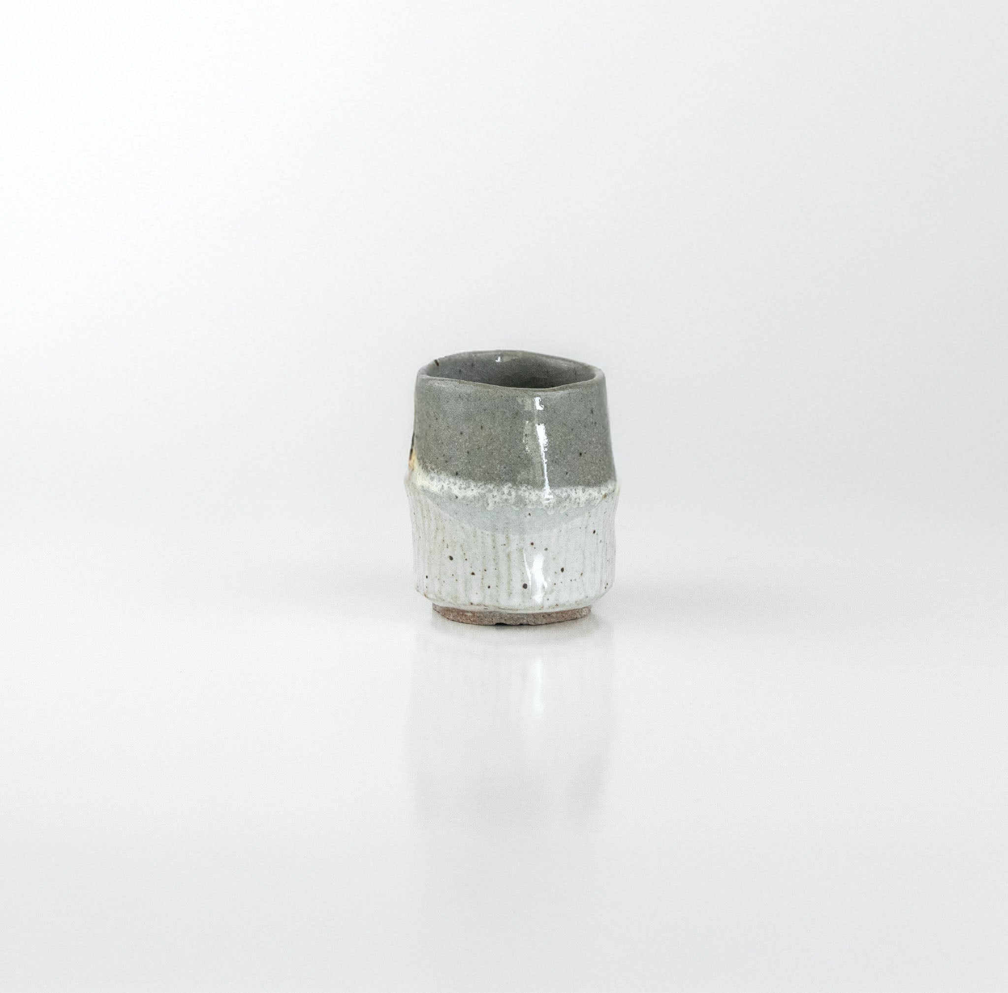 Hand-thrown ceramic sake cup with contrasting matte and glossy grey glazes, by The Lazy Potters.