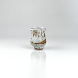 Flared handmade ceramic sake cup with white drip glaze and ribbed clay base, by The Lazy Potters.