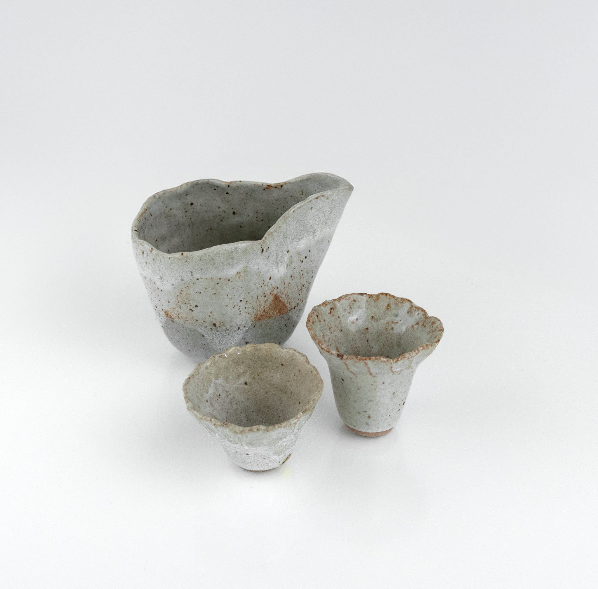 One-of-a-kind ceramic sake set featuring a rippled pourer and two textured cups in white speckled glaze by The Lazy Potters.