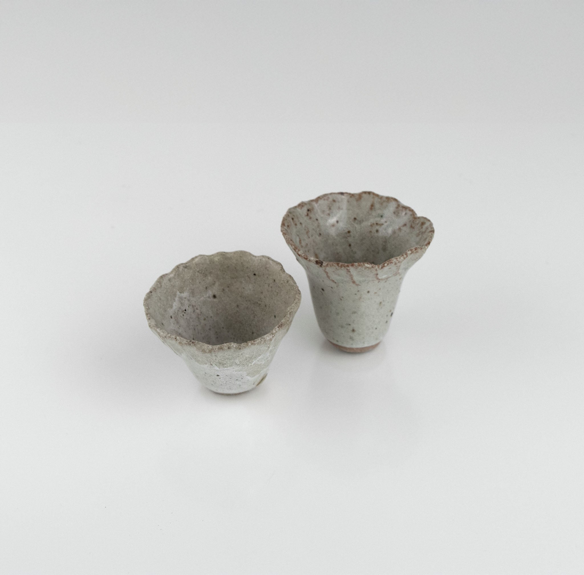 One-of-a-kind ceramic sake set featuring a rippled pourer and two textured cups in white speckled glaze by The Lazy Potters.