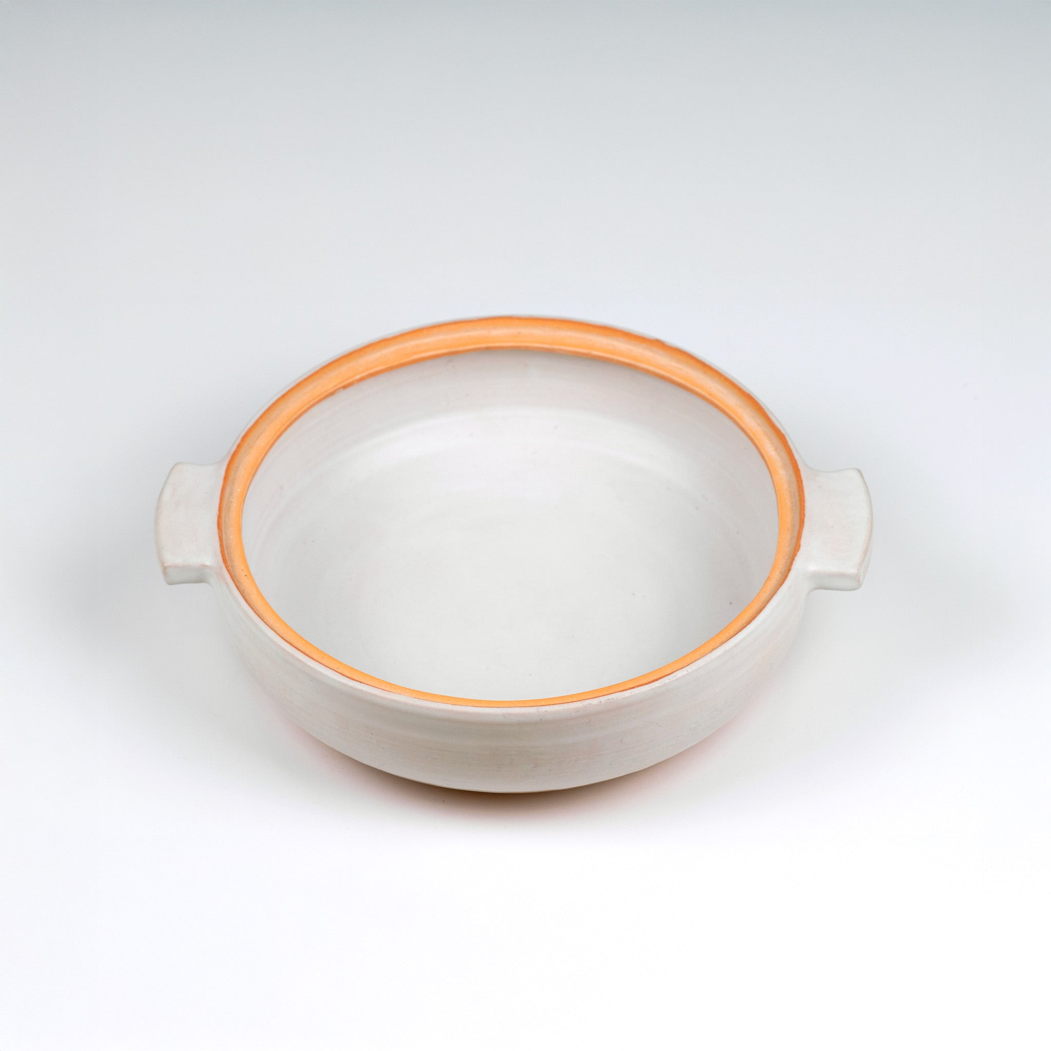 Limited edition off-white ceramic ttukbaegi  pot only with terrapcotta colored rim on a white background