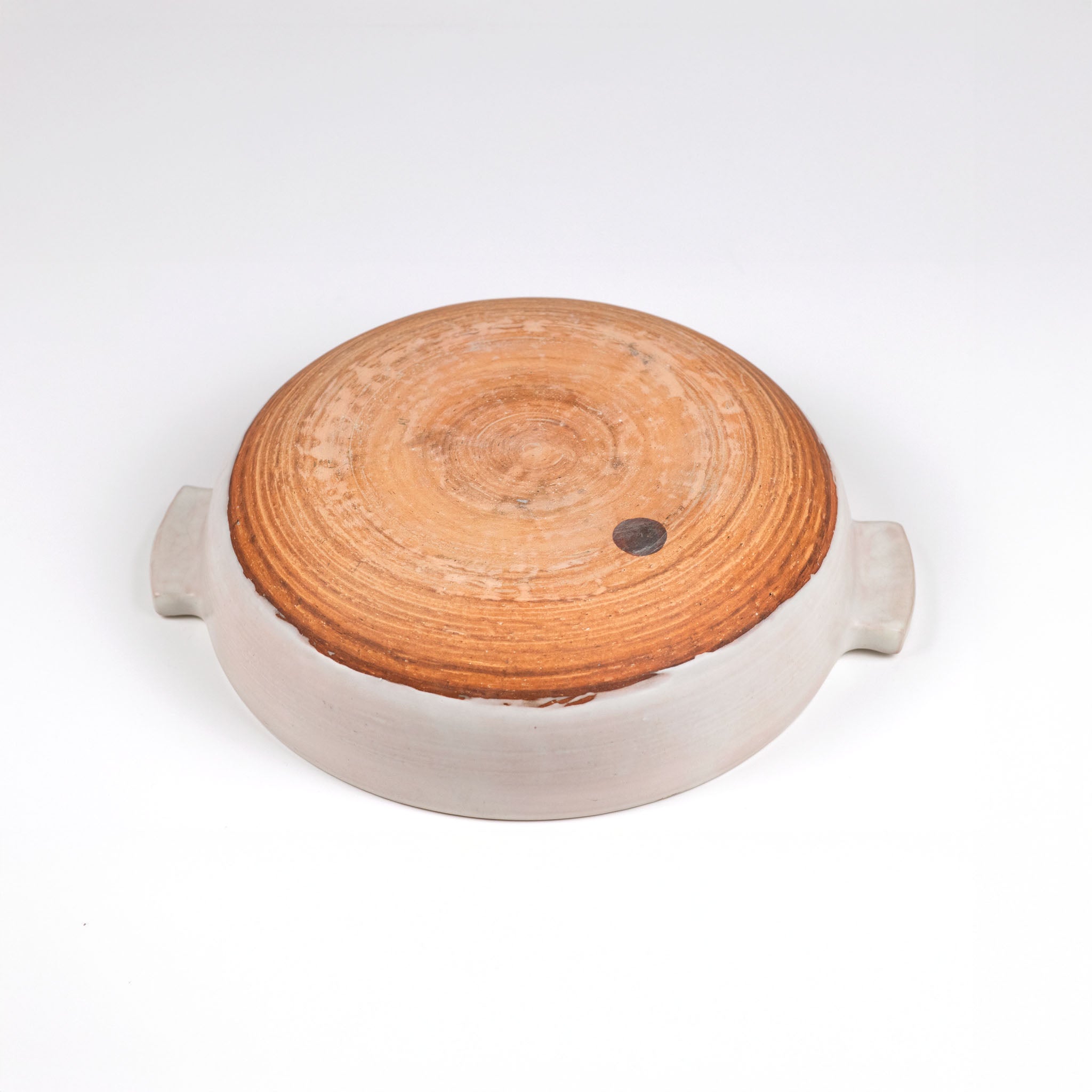 The underside of the limited edition off-white ceramic ttukbaegi with terrapcotta colored  base on a white background