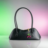 Black handbag with cherry charm on a gradient background