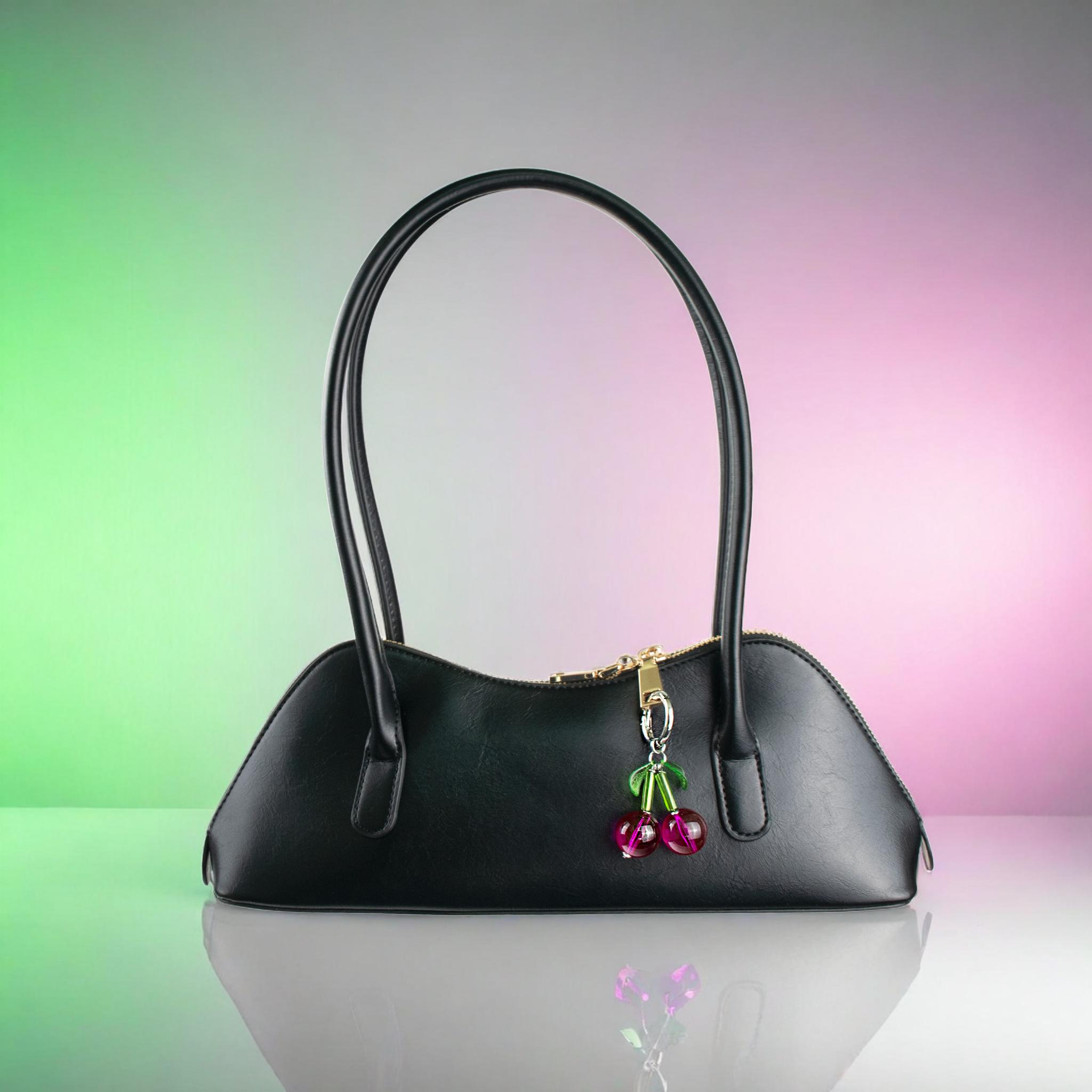 Black handbag with cherry charm on a gradient background