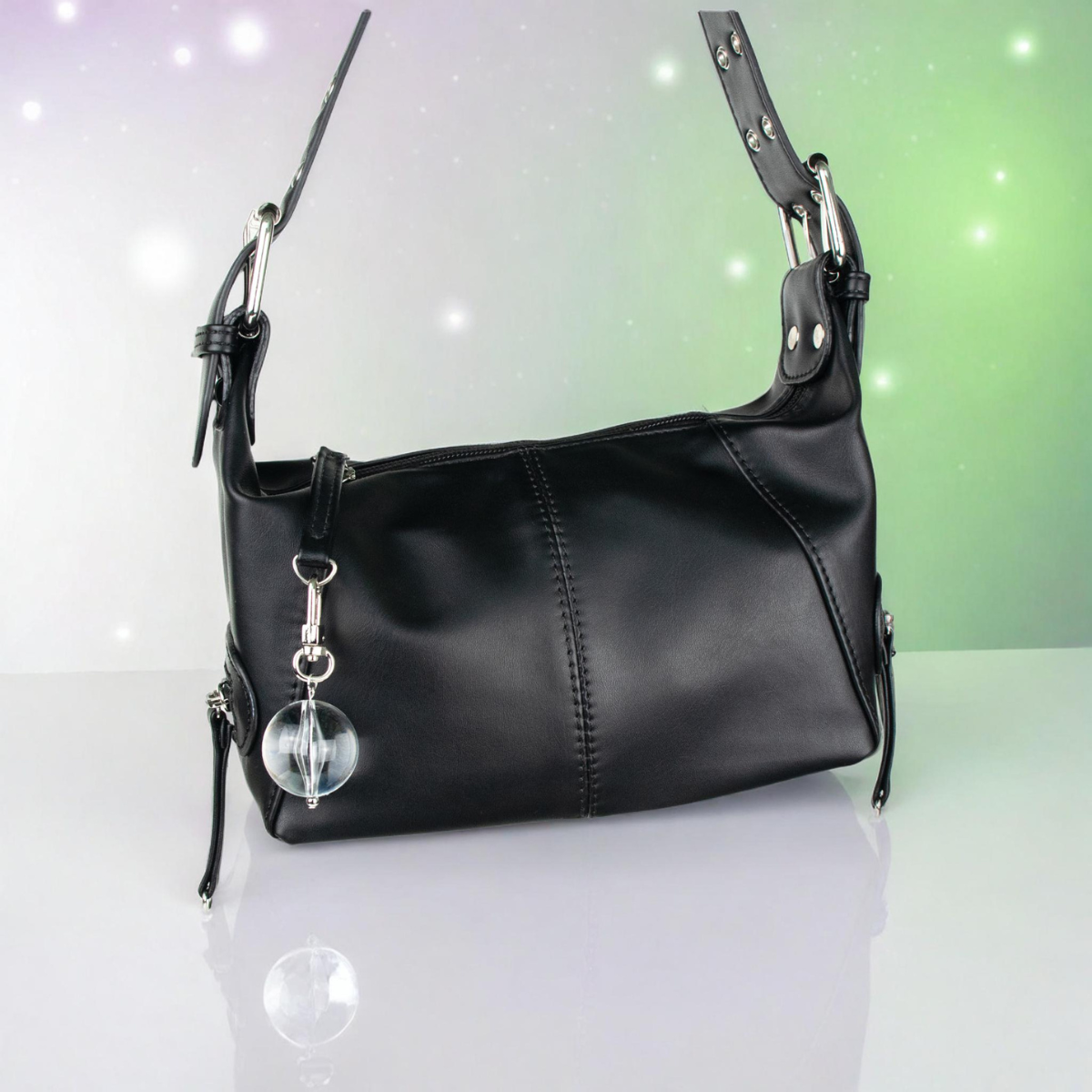 Black handbag with a round clear ball designed keychain on a gradient background