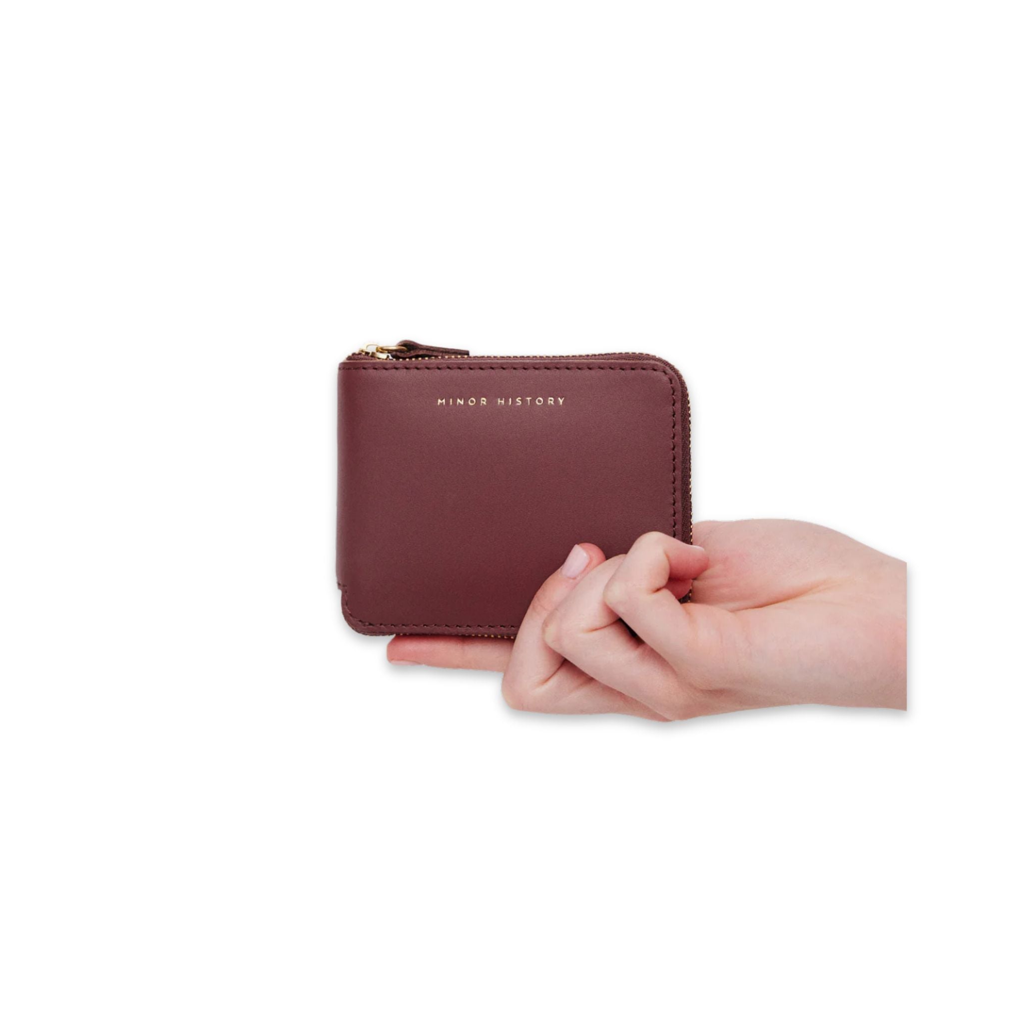 A hand model holding Minor History's The Coupe Wallet in color barbera