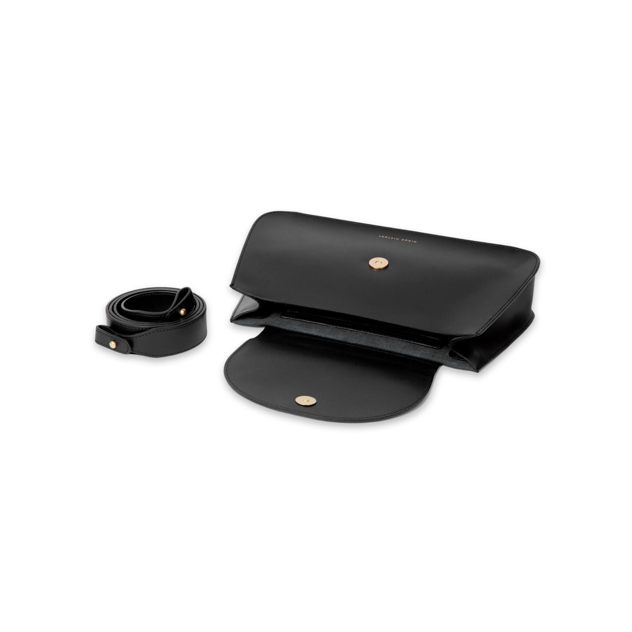 Image of Minor History's The Horizon Crossbody bag in black laying flat open with shoulder straps disconnected and coiled next to bag