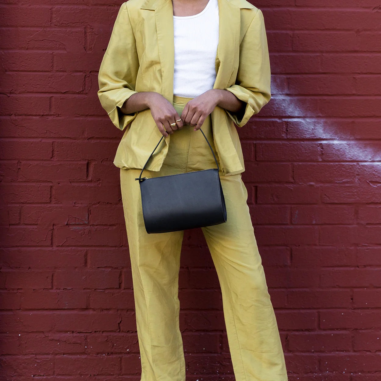 A model holding Minor History's The Hug Shoulder bag in color black