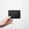 Image of a hand model holding Minor History metro card case black