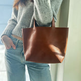 A model wearing a grey sweater and blue jeans carrying the Nimes Gorriti Saddle Hand Bag