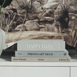 lifestyle image of open printworks photo album happy days grey design lying ontop of two books 