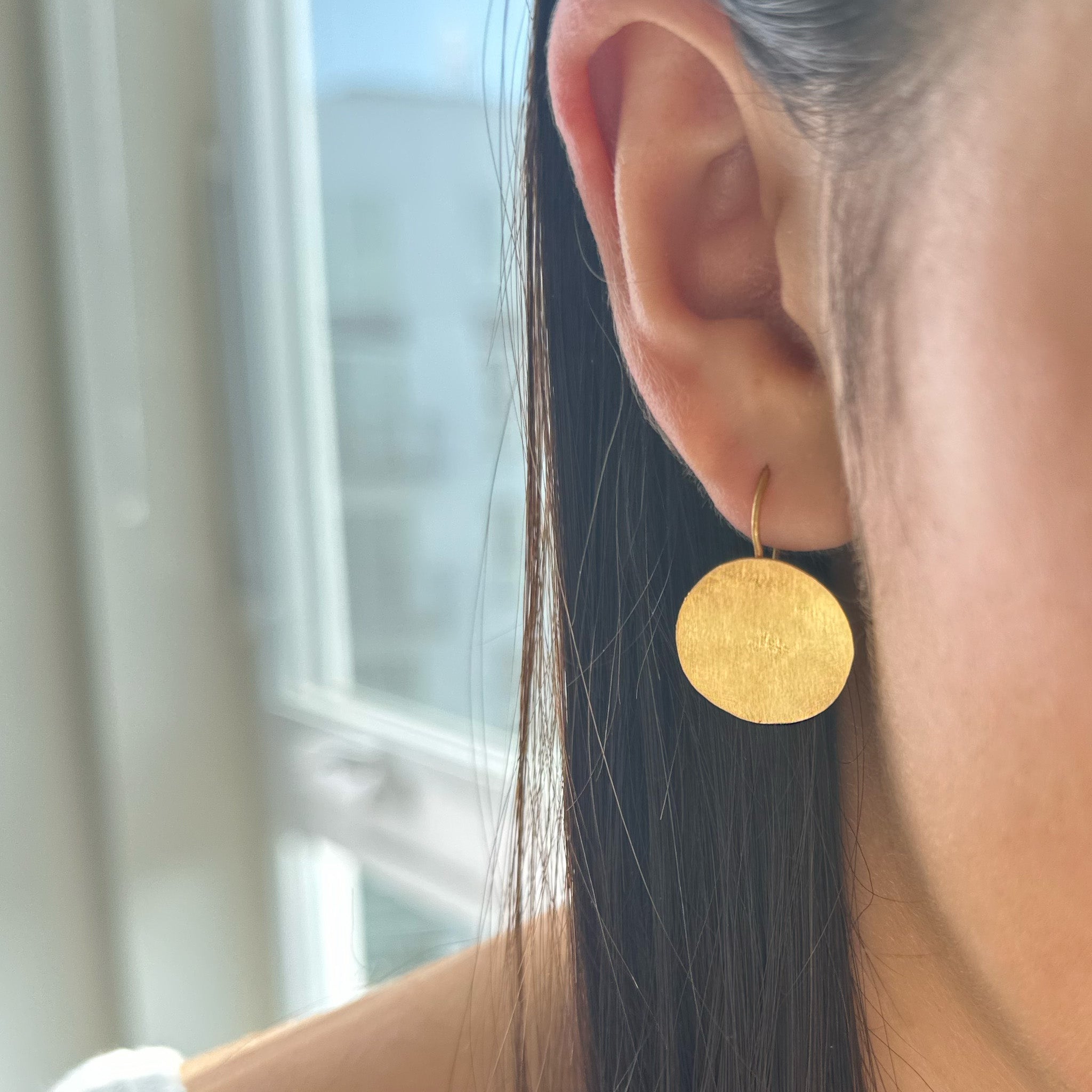 image of model wearing river song earring handcut gold coin design