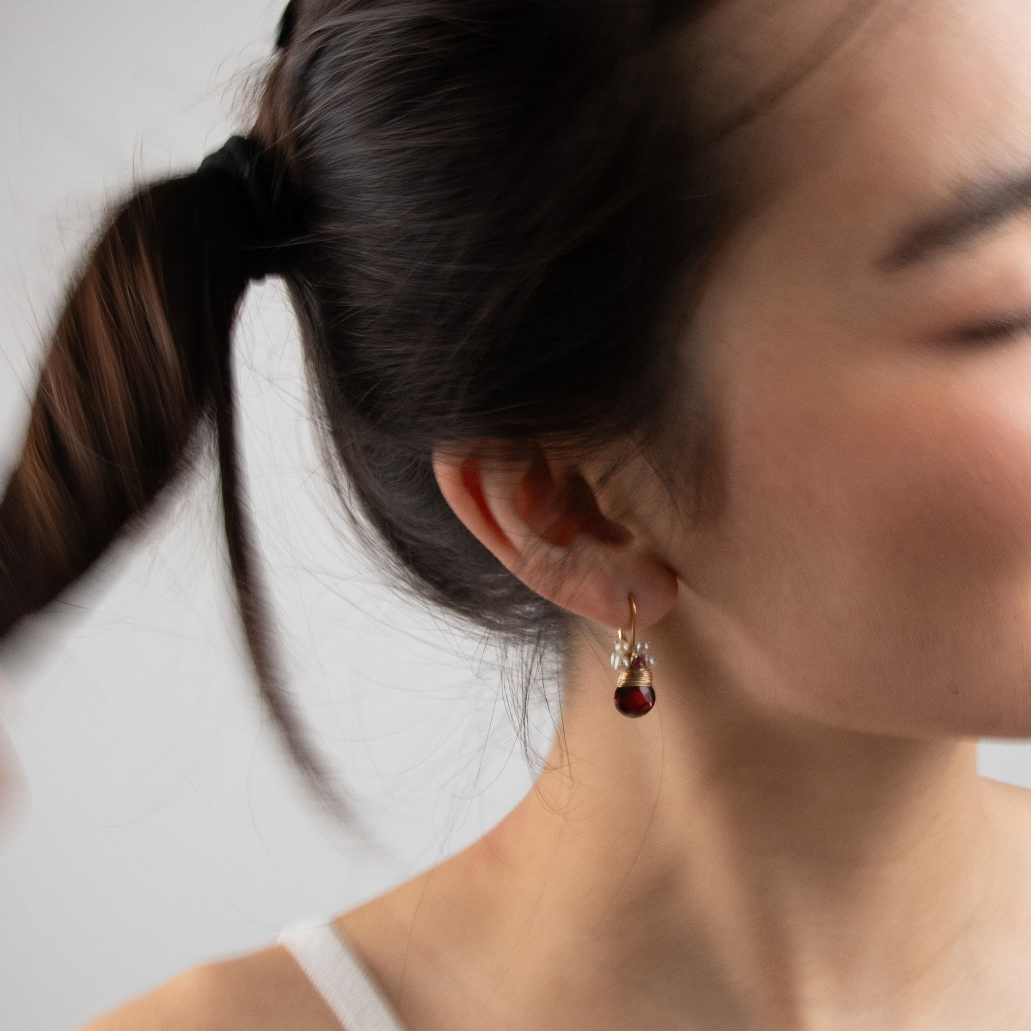 A close up of a model wearing River Song's Regal Garnet Fringe earrings.