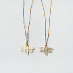 close up image of two see real flowers necklace next to each other with dragonfly design