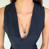 Person wearing a dark blue sleeveless top with See Real Flowers Trinket necklace in indigo.