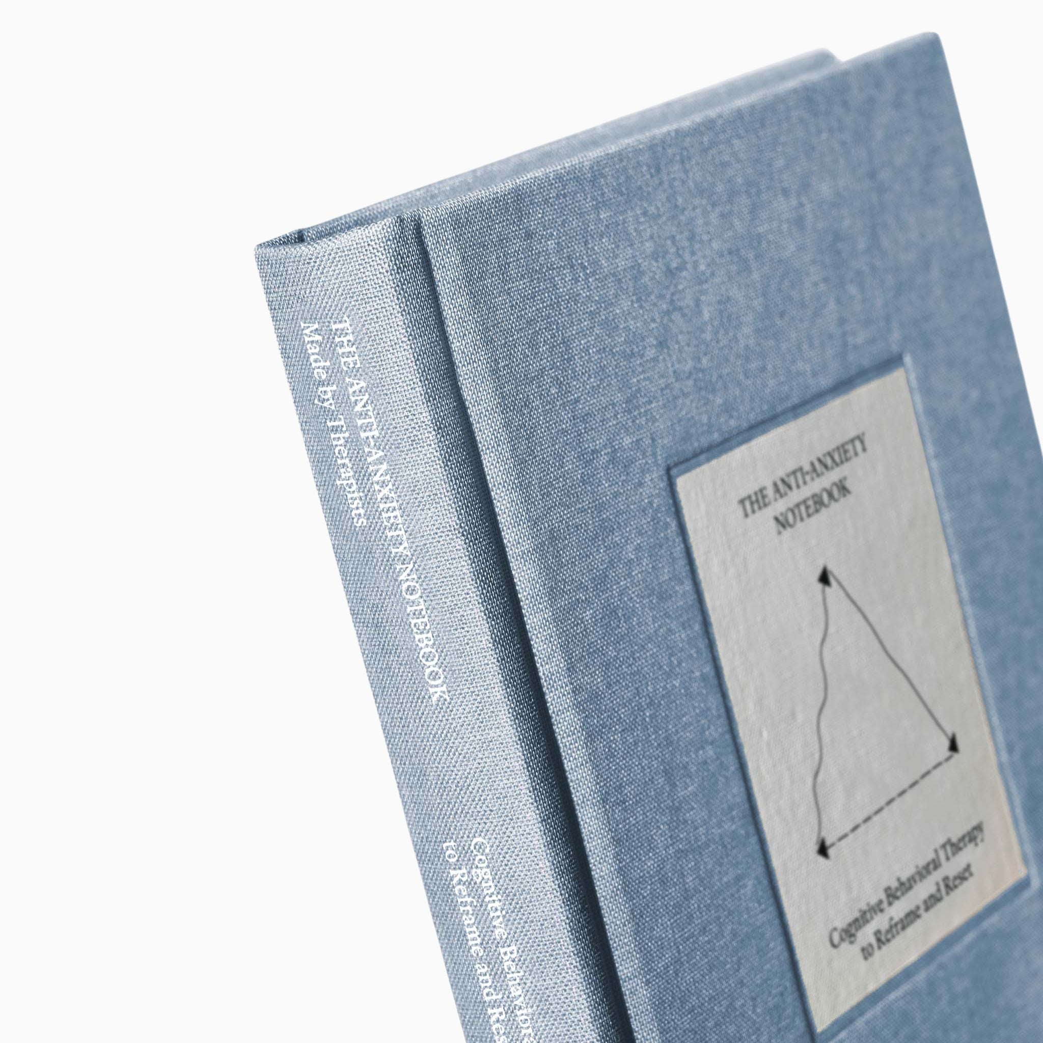 Close-up of The Anti-Anxiety Notebook by Therapy Notebooks, featuring a linen hardcover with a minimalist stitched patch and embossed spine text.