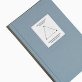 Top view of The Anti-Anxiety Notebook by Therapy Notebooks, featuring a linen hardcover with a minimalist stitched patch and embossed spine text.