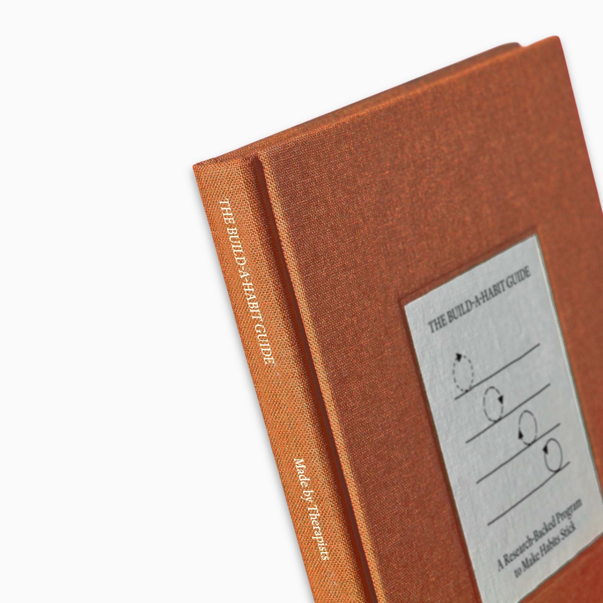 Close-up of The Build A Habit Guide by Therapy Notebooks, featuring a linen hardcover with a minimalist stitched patch and embossed spine text.