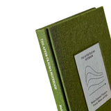 Close-up of The After Trauma Notebook by Therapy Notebooks, featuring a linen hardcover with a minimalist stitched patch and embossed spine text.
