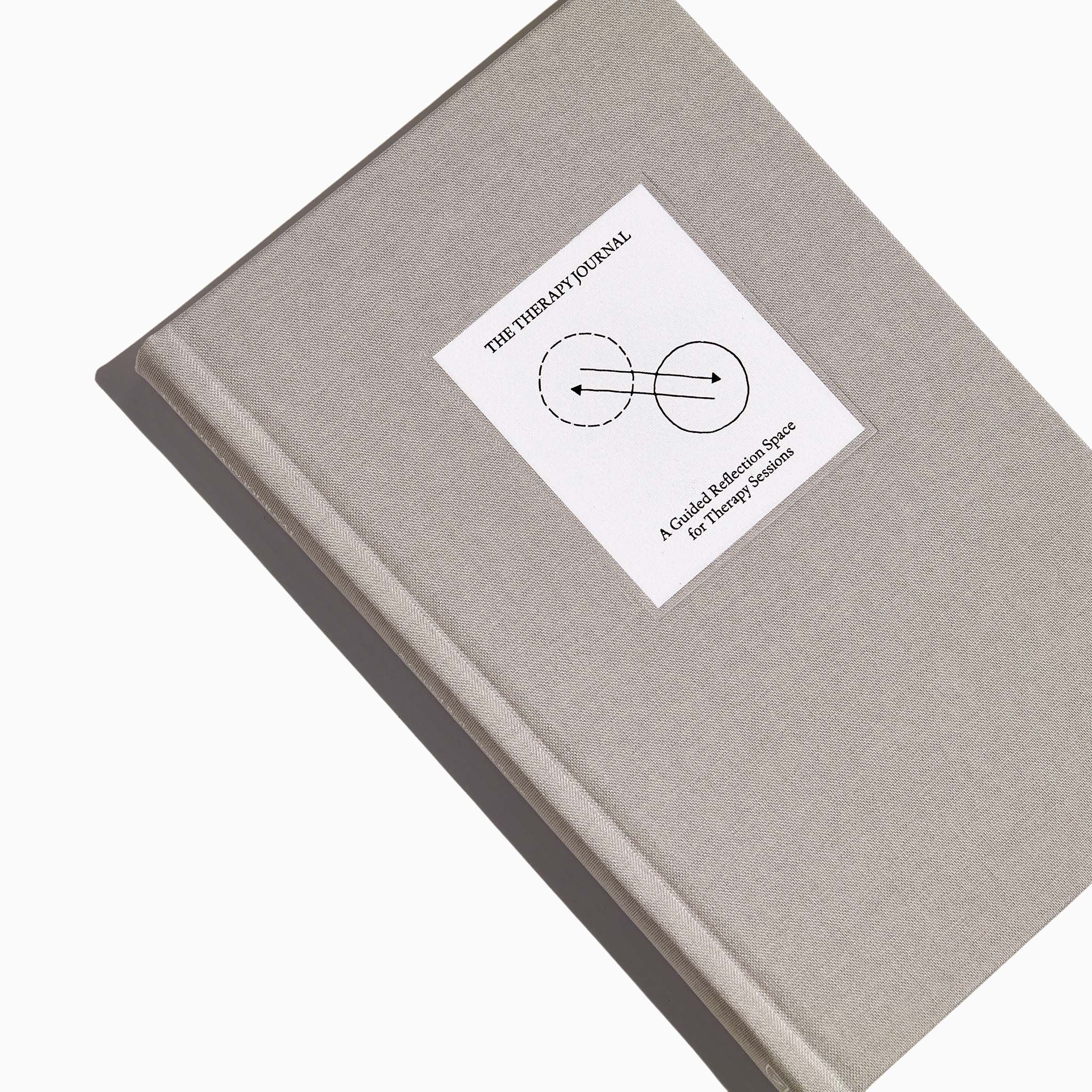 Top view of The Therapy Journal by Therapy Notebooks, featuring a linen hardcover with a minimalist stitched patch and embossed spine text.