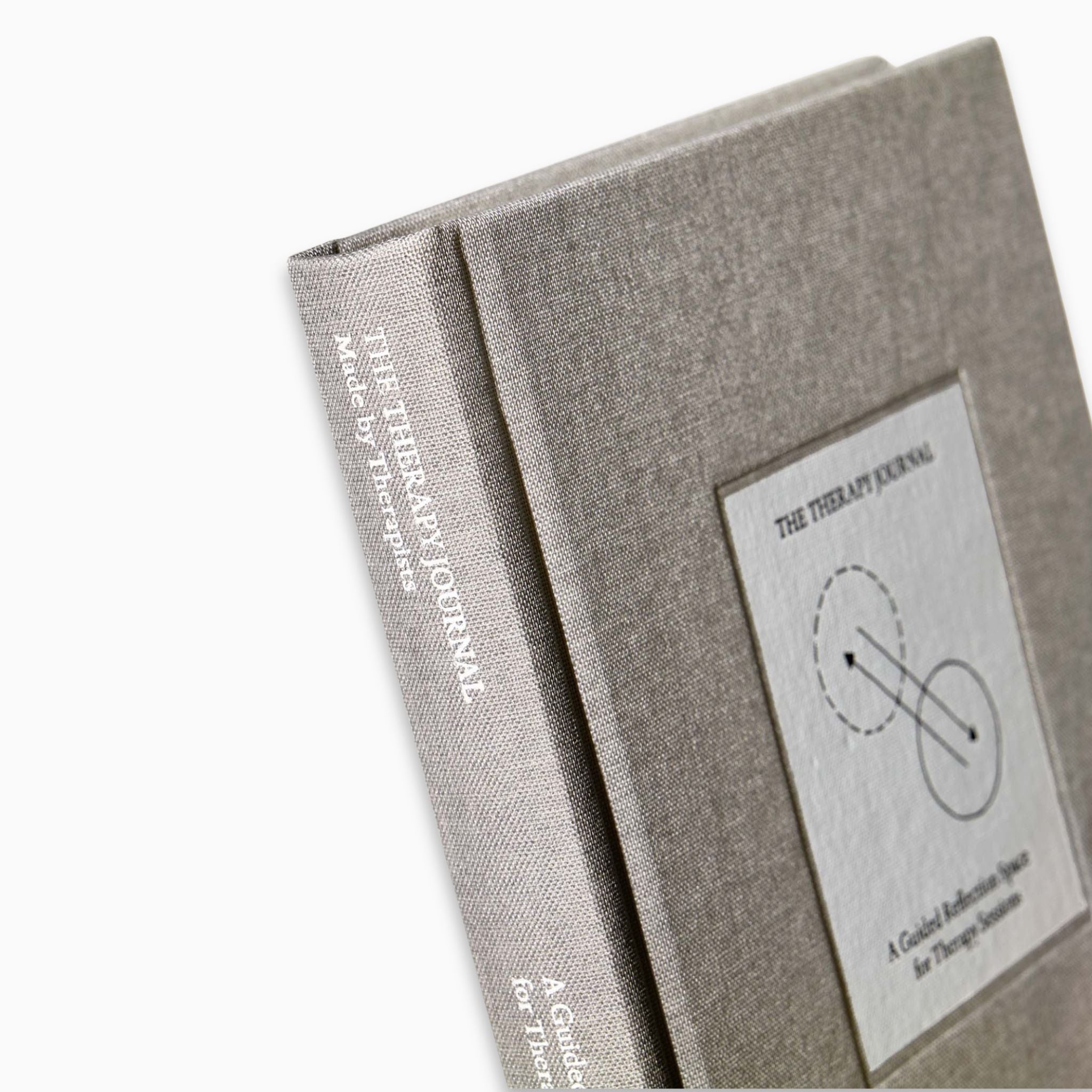 Close-up of The Therapy Journal by Therapy Notebooks, featuring a linen hardcover with a minimalist stitched patch and embossed spine text.
