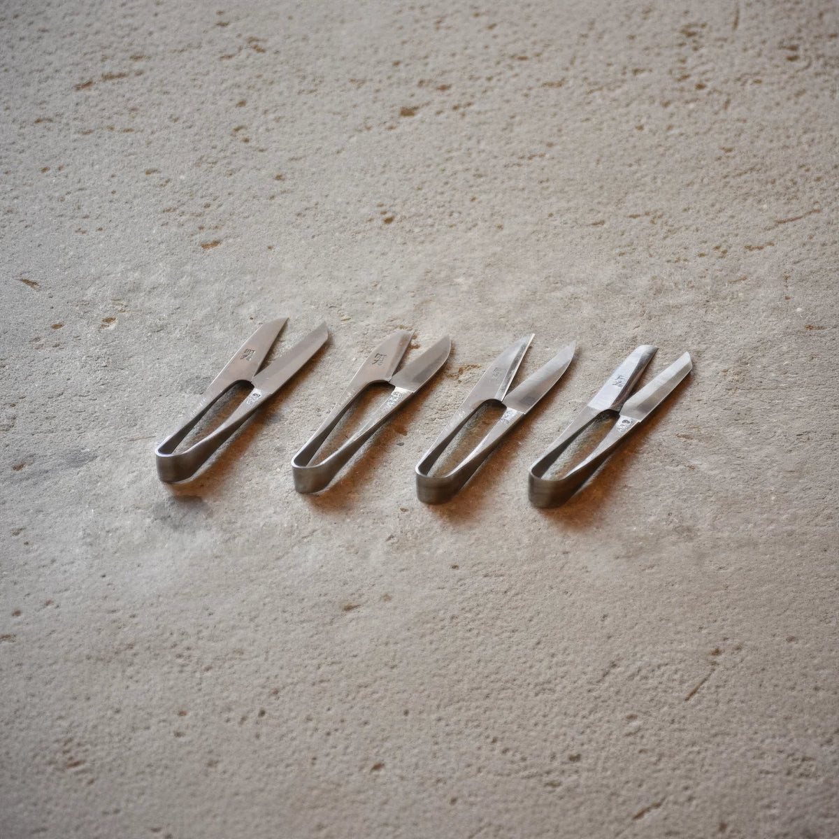 Set of four Terazaki Hamono Tsume Scissors on a textured surface