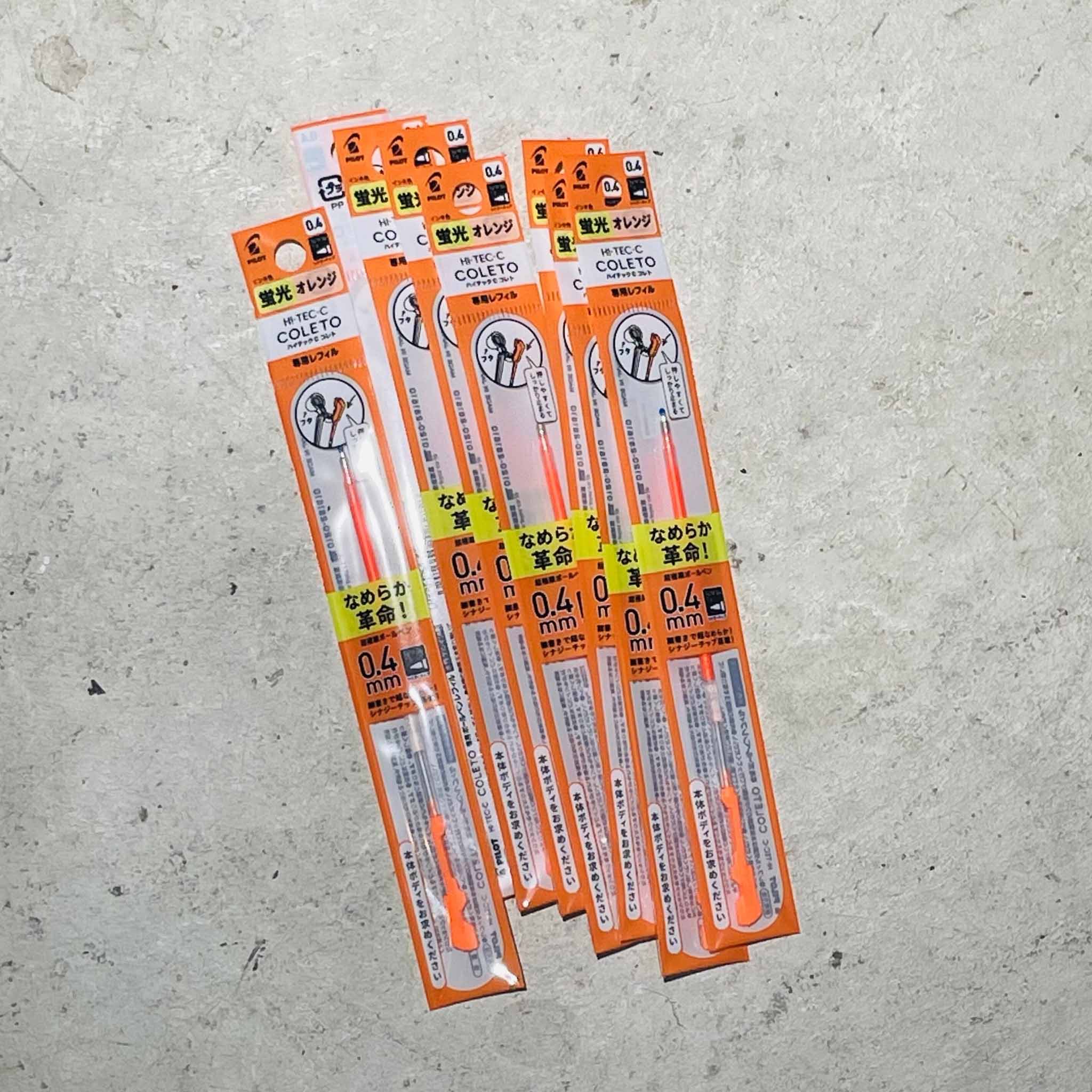 A bunch of Coletto Hi-Tec-C pen orange refills on a gray background