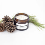 image of an open jar of terralite scented candles nordic pine scent next to pine cones