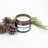 image of an open jar of terralite scented candles nordic pine scent next to pine cones