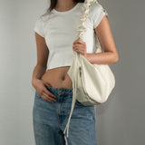 Image of a model carrying Melie Bianco's Reign shoulder bag in ivory