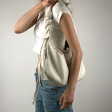 Image of a model carrying Melie Bianco's Reign shoulder bag in ivory
